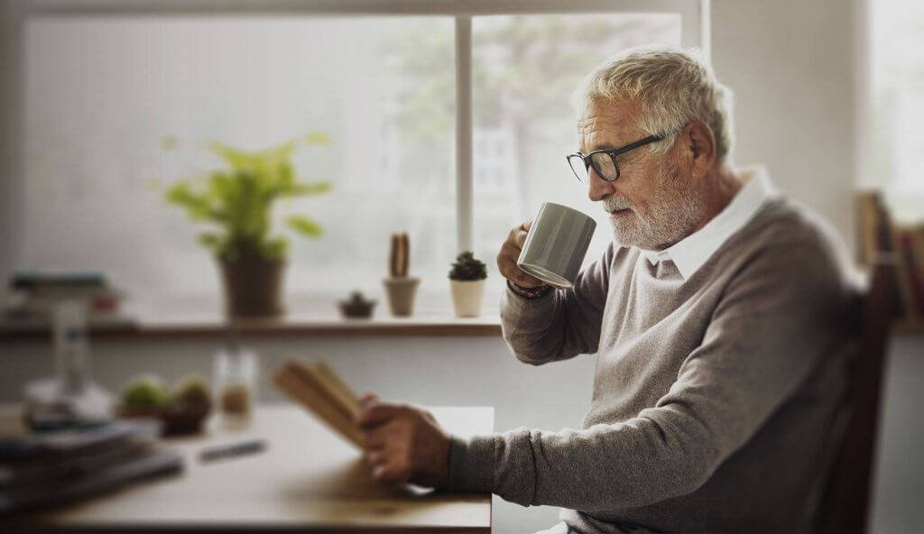 Old man drinking tea coffee reading paper